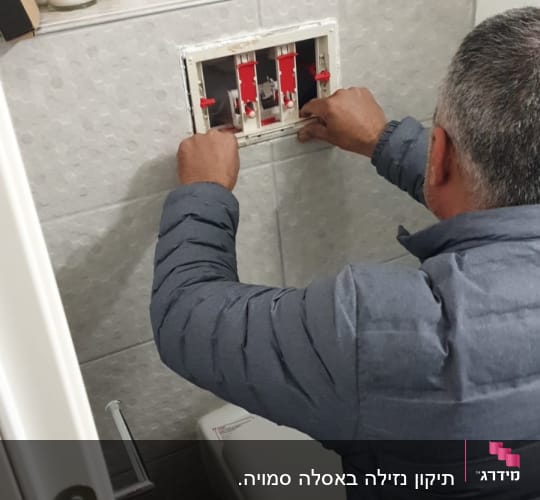 אדם מתקן מערכת מים בקיר חדר אמבטיה